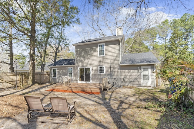 rear view of property featuring a chimney, fence, and a deck