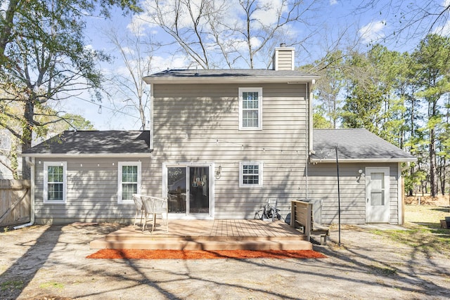 back of property with a deck, a chimney, and fence