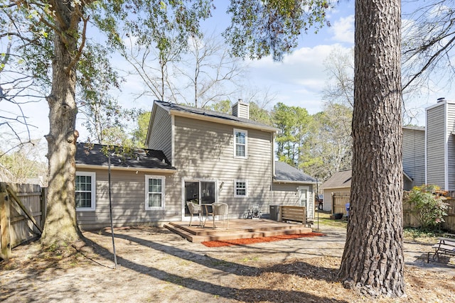 rear view of property featuring fence, a chimney, and a wooden deck