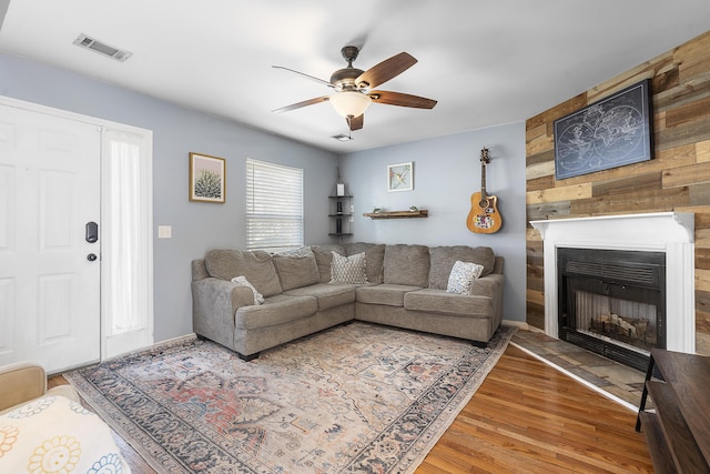 living room with baseboards, visible vents, a ceiling fan, wood finished floors, and a fireplace