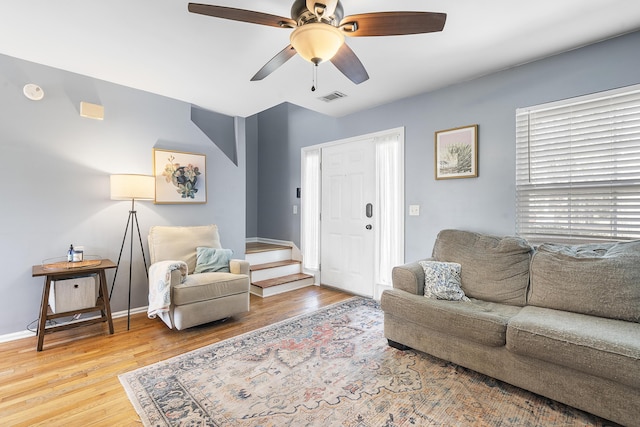 living room featuring stairway, a ceiling fan, visible vents, and wood finished floors