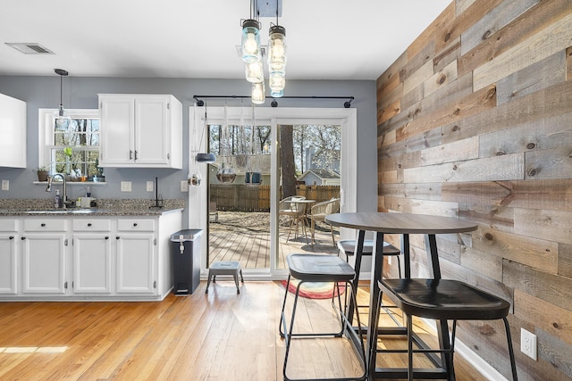 dining room featuring light wood finished floors, wooden walls, and visible vents