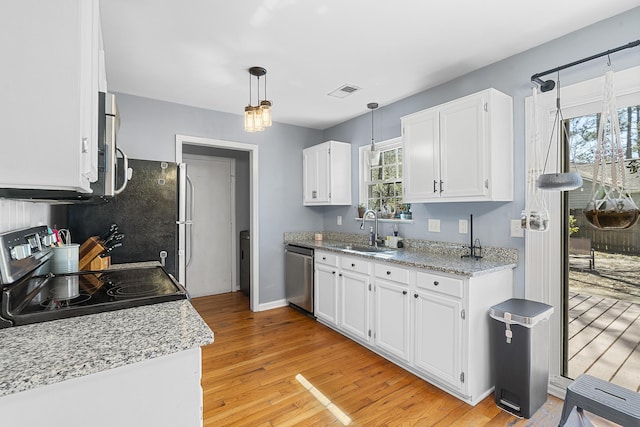 kitchen featuring visible vents, light wood-style flooring, stainless steel appliances, white cabinetry, and a sink