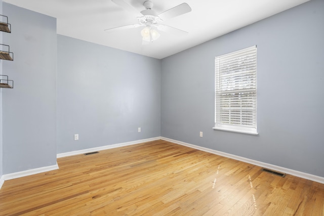 spare room with ceiling fan, light wood-type flooring, visible vents, and baseboards