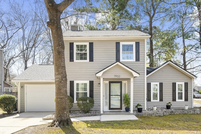 colonial house with driveway, a shingled roof, a chimney, an attached garage, and a front yard