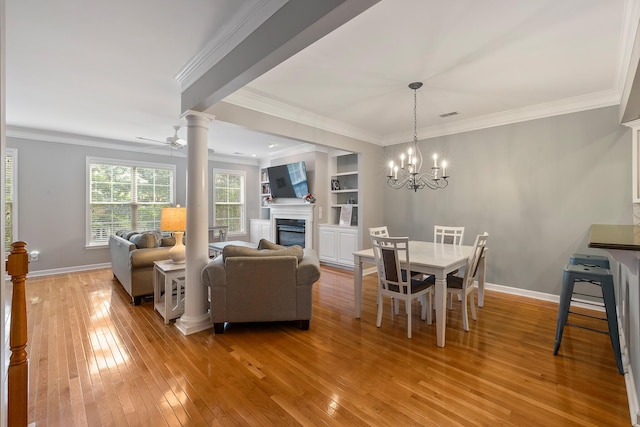 167 Palm Cove Way, Mount Pleasant, SC 29466 - dining area with light wood-style floors, a glass covered fireplace, crown molding, decorative columns, and a chandelier