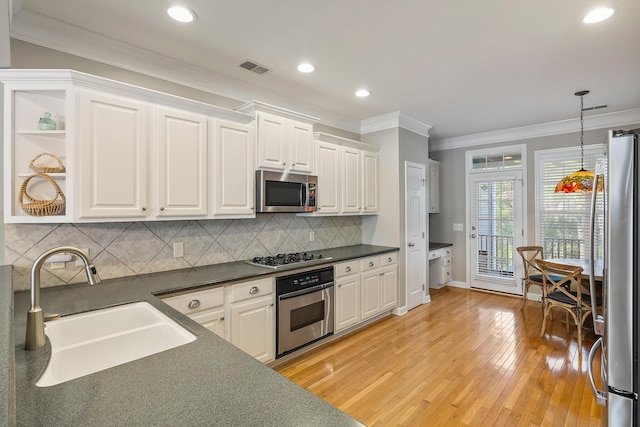 167 Palm Cove Way, Mount Pleasant, SC 29466 - kitchen with appliances with stainless steel finishes, dark countertops, white cabinets, ornamental molding, and light wood-type flooring