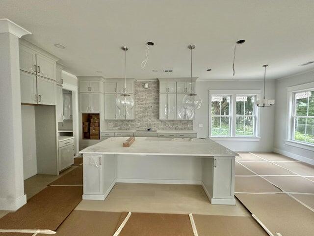 kitchen featuring tasteful backsplash, a spacious island, light countertops, hanging light fixtures, and white cabinets