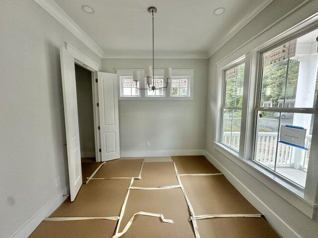 unfurnished dining area with baseboards and crown molding