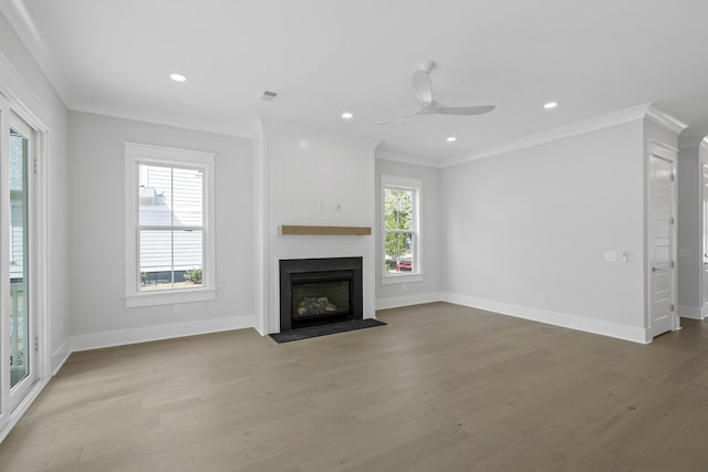 unfurnished living room with light wood finished floors, a fireplace, visible vents, and crown molding