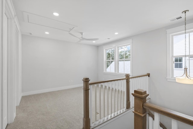 hallway featuring carpet, visible vents, attic access, an upstairs landing, and baseboards