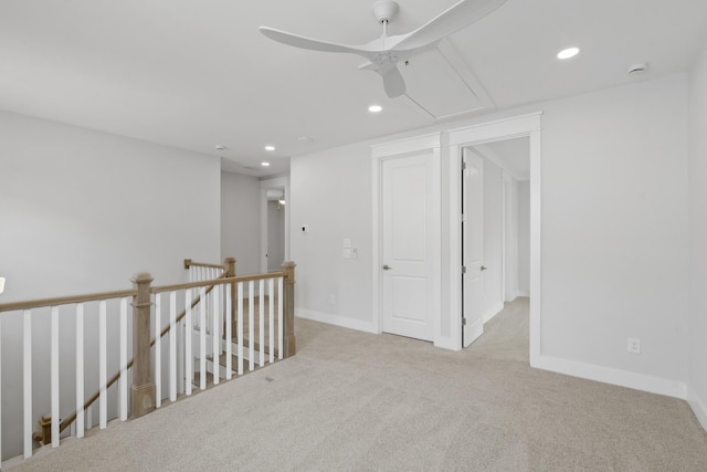 empty room featuring carpet floors, recessed lighting, attic access, a ceiling fan, and baseboards