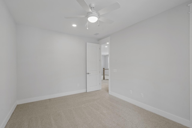 empty room featuring light colored carpet, ceiling fan, and baseboards