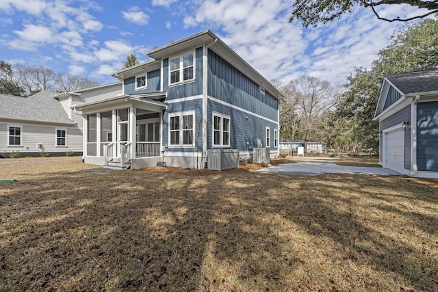 back of property featuring board and batten siding, a yard, a garage, and a porch