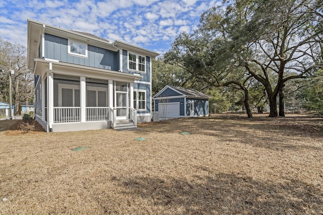 back of house featuring a sunroom, a detached garage, board and batten siding, and an outdoor structure