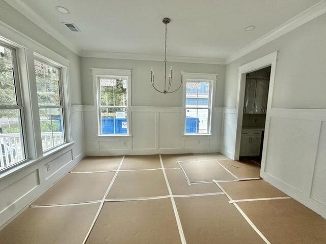 unfurnished dining area featuring a wainscoted wall, visible vents, and a healthy amount of sunlight