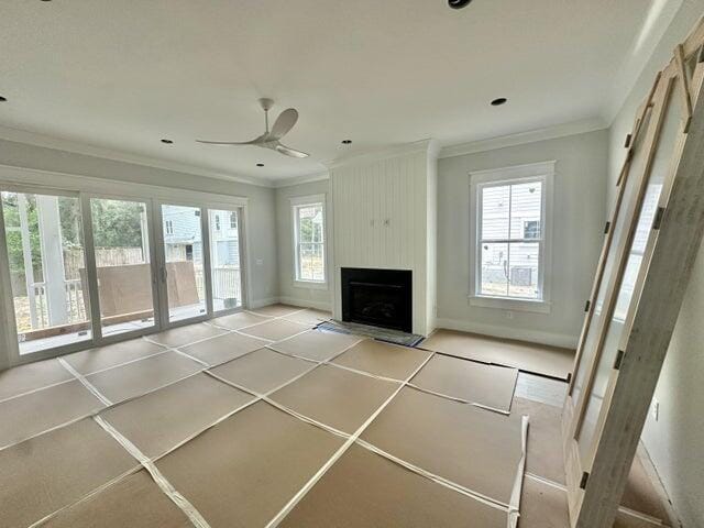 unfurnished living room featuring a large fireplace, baseboards, a ceiling fan, and crown molding