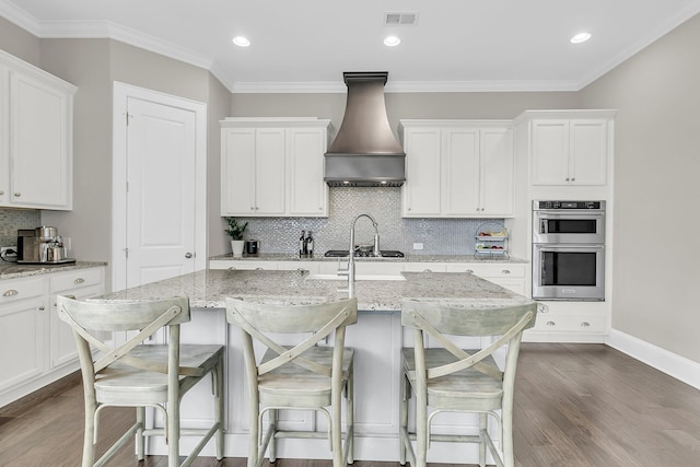 2072 Amenity Park Dr, Mount Pleasant, SC 29466 - kitchen featuring custom exhaust hood, dark wood finished floors, tasteful backsplash, a breakfast bar, and crown molding