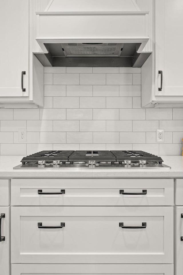 details featuring white cabinets, custom range hood, and tasteful backsplash