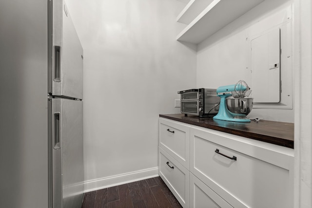 kitchen featuring white cabinets, dark hardwood / wood-style floors, stainless steel fridge, and electric panel