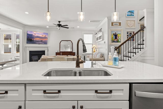 kitchen with white cabinets, sink, hanging light fixtures, ceiling fan, and ornamental molding