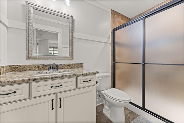 bathroom featuring vanity, toilet, and a shower with door