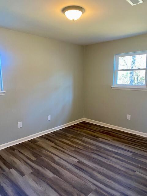 empty room with visible vents, baseboards, and dark wood-style flooring