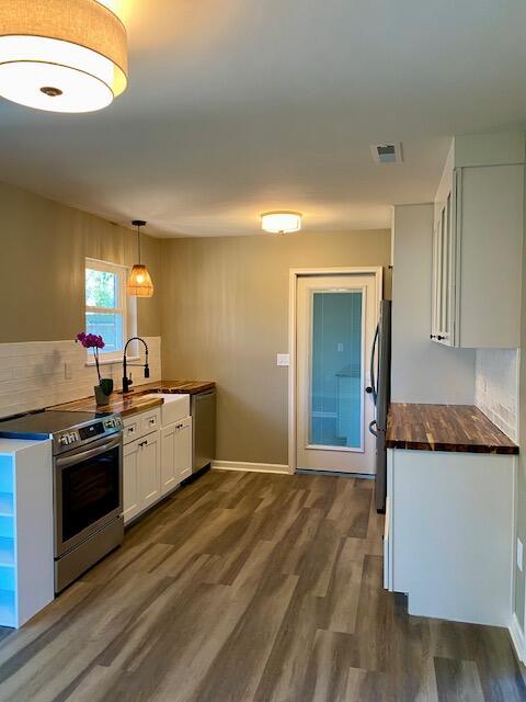 kitchen featuring dark wood-style floors, a sink, white cabinets, appliances with stainless steel finishes, and backsplash