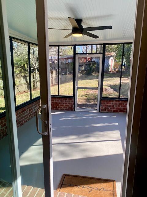 unfurnished sunroom with ceiling fan