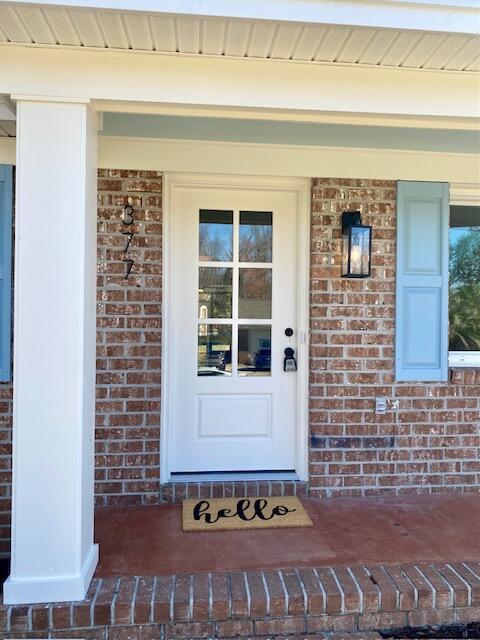 property entrance featuring brick siding and covered porch