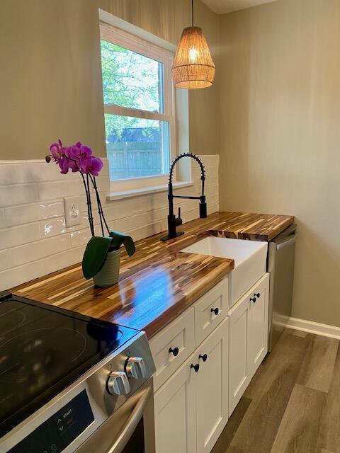 kitchen featuring dark wood-style floors, electric range, wood counters, white cabinetry, and tasteful backsplash