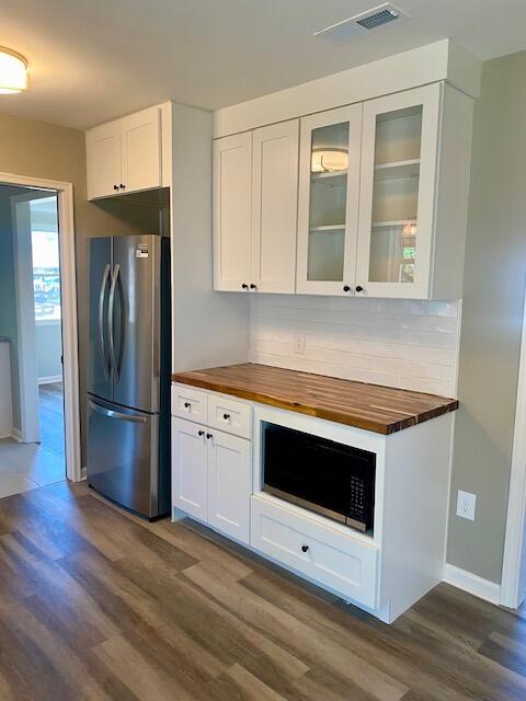 kitchen with visible vents, wooden counters, white cabinetry, and freestanding refrigerator