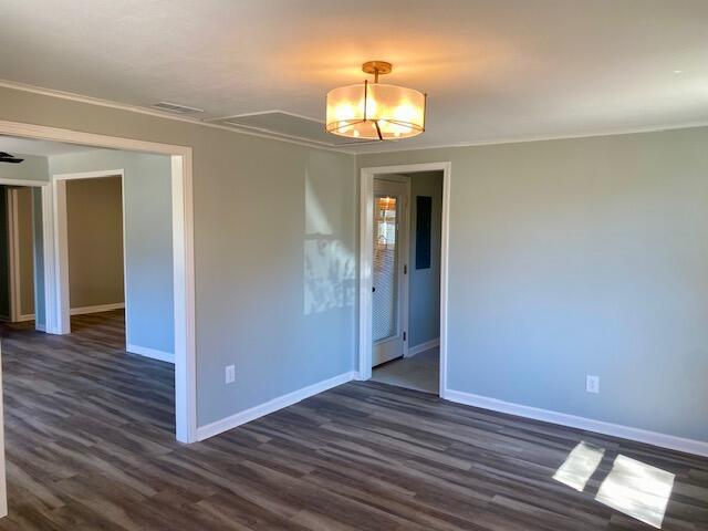 unfurnished room with dark wood finished floors, visible vents, and baseboards