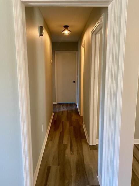 corridor featuring baseboards and dark wood finished floors