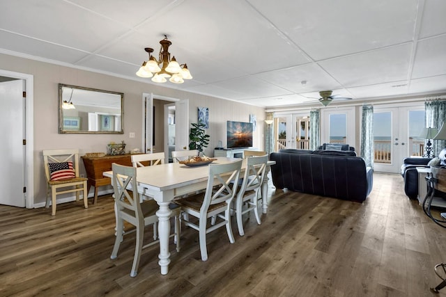 dining space featuring crown molding, dark wood-type flooring, an inviting chandelier, and french doors