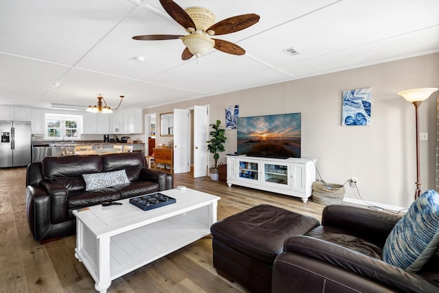 living room with hardwood / wood-style floors and ceiling fan with notable chandelier