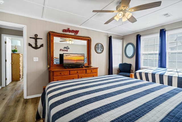 bedroom with wood-type flooring, ornamental molding, and ceiling fan