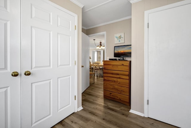 corridor featuring crown molding, wood-type flooring, and a chandelier