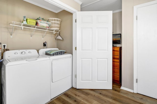 laundry area featuring crown molding, separate washer and dryer, and hardwood / wood-style floors