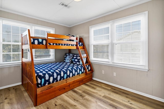 bedroom with crown molding, light hardwood / wood-style floors, and multiple windows