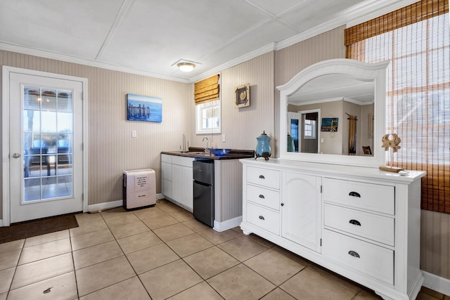 kitchen with sink, crown molding, white cabinetry, fridge, and light tile patterned flooring