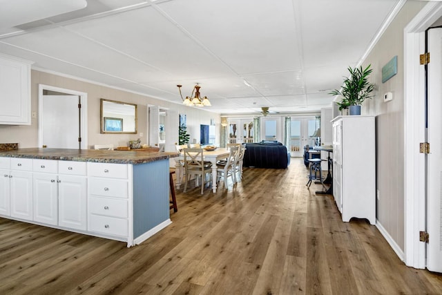 kitchen featuring a breakfast bar area, white cabinetry, hardwood / wood-style floors, ornamental molding, and kitchen peninsula