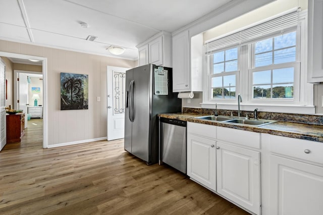 kitchen featuring sink, white cabinetry, ornamental molding, appliances with stainless steel finishes, and light hardwood / wood-style floors