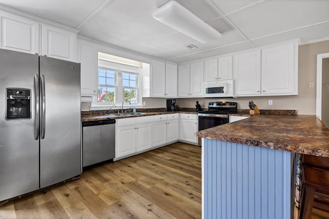 kitchen with sink, appliances with stainless steel finishes, white cabinets, kitchen peninsula, and light wood-type flooring