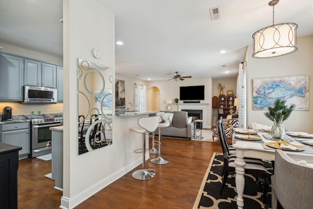 kitchen featuring dark hardwood / wood-style flooring, decorative light fixtures, light stone countertops, and appliances with stainless steel finishes