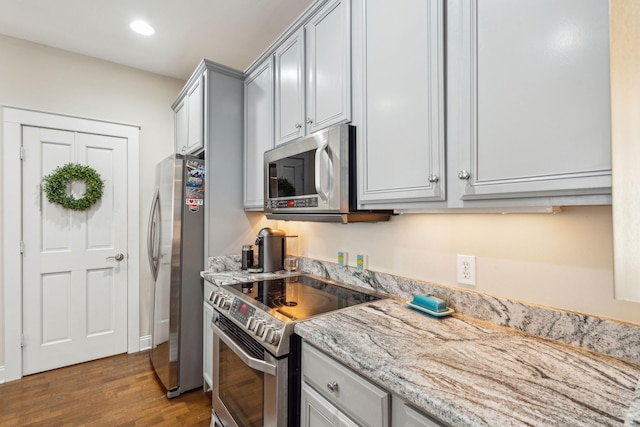 kitchen featuring appliances with stainless steel finishes, light stone countertops, hardwood / wood-style floors, and gray cabinetry