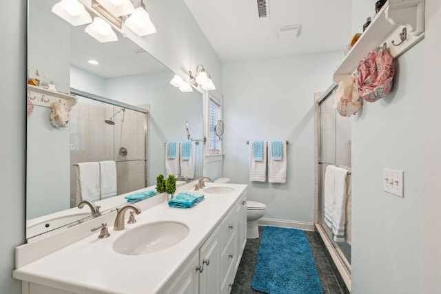 bathroom with tile patterned floors, vanity, toilet, and a shower with shower door