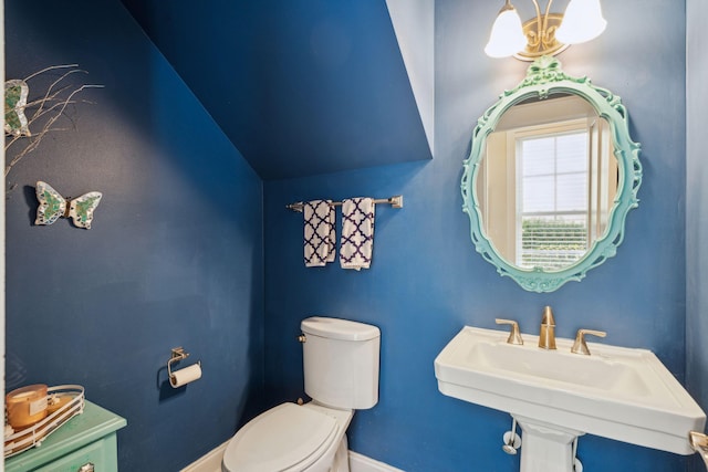 bathroom with toilet, a chandelier, and sink