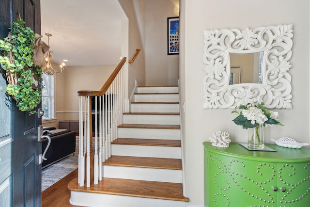 stairway featuring a notable chandelier and wood-type flooring