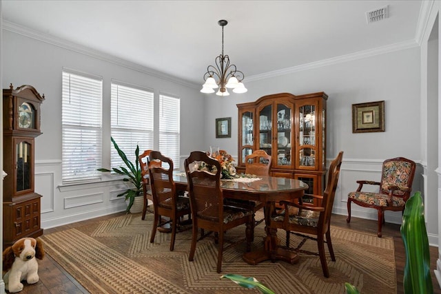 dining area with crown molding, hardwood / wood-style floors, and an inviting chandelier